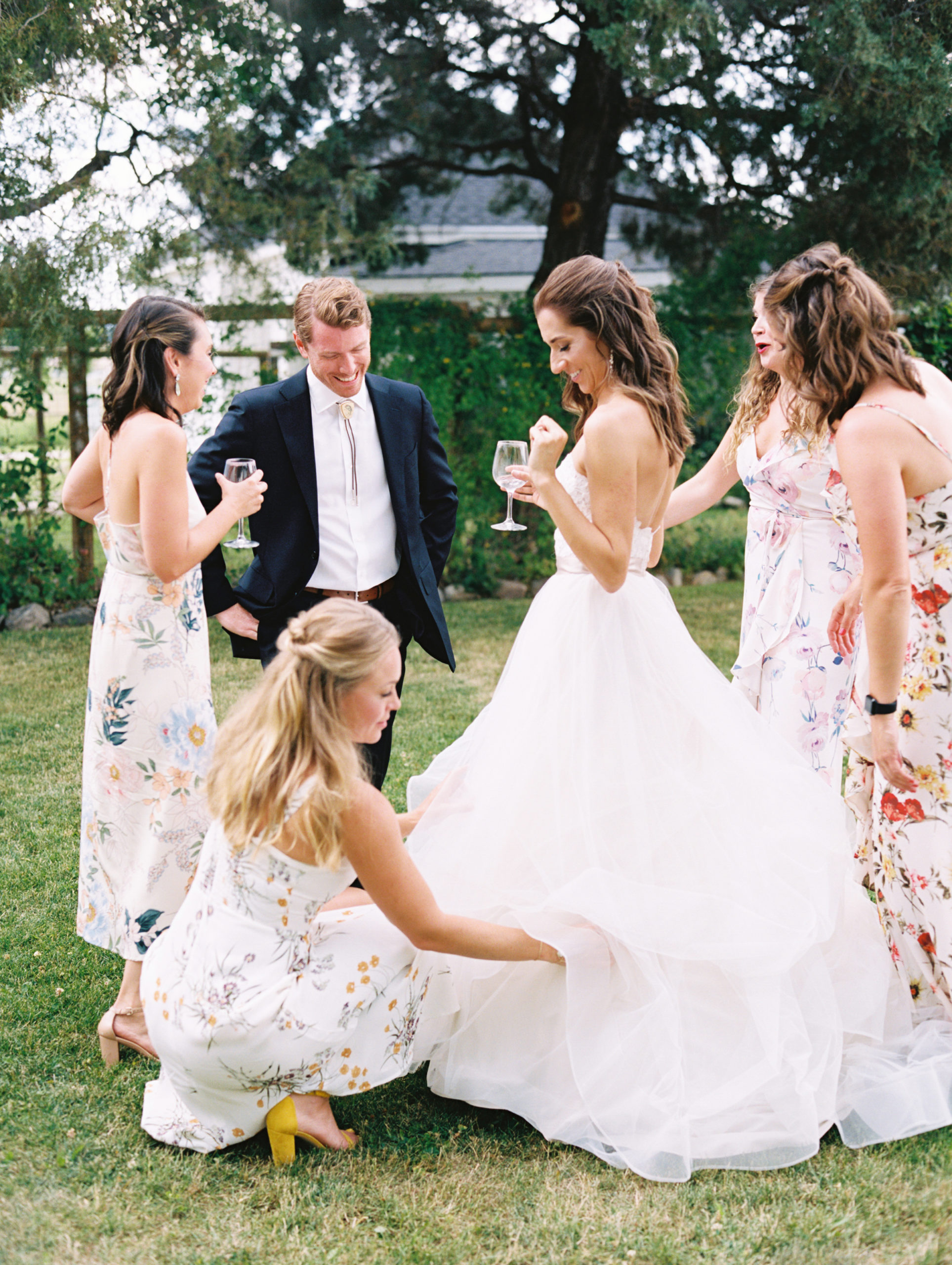 candid wedding photo of bridesmaids helping bride with her wedding dress