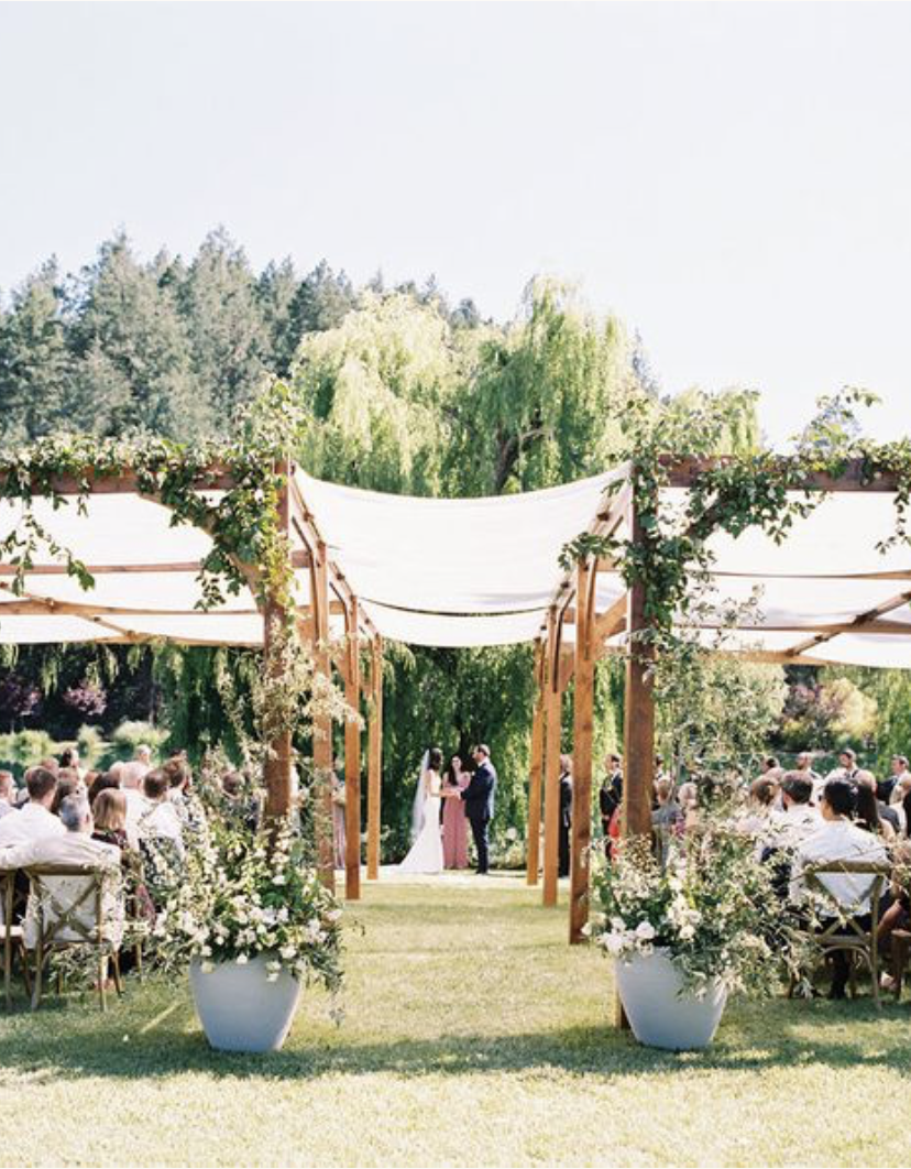 outdoor wedding ceremony with guests under canopy and floral wedding arch at black swan lake wedding venue in Napa valley